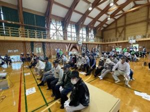 段ボールベッドを椅子代わりに座る訓練参加者